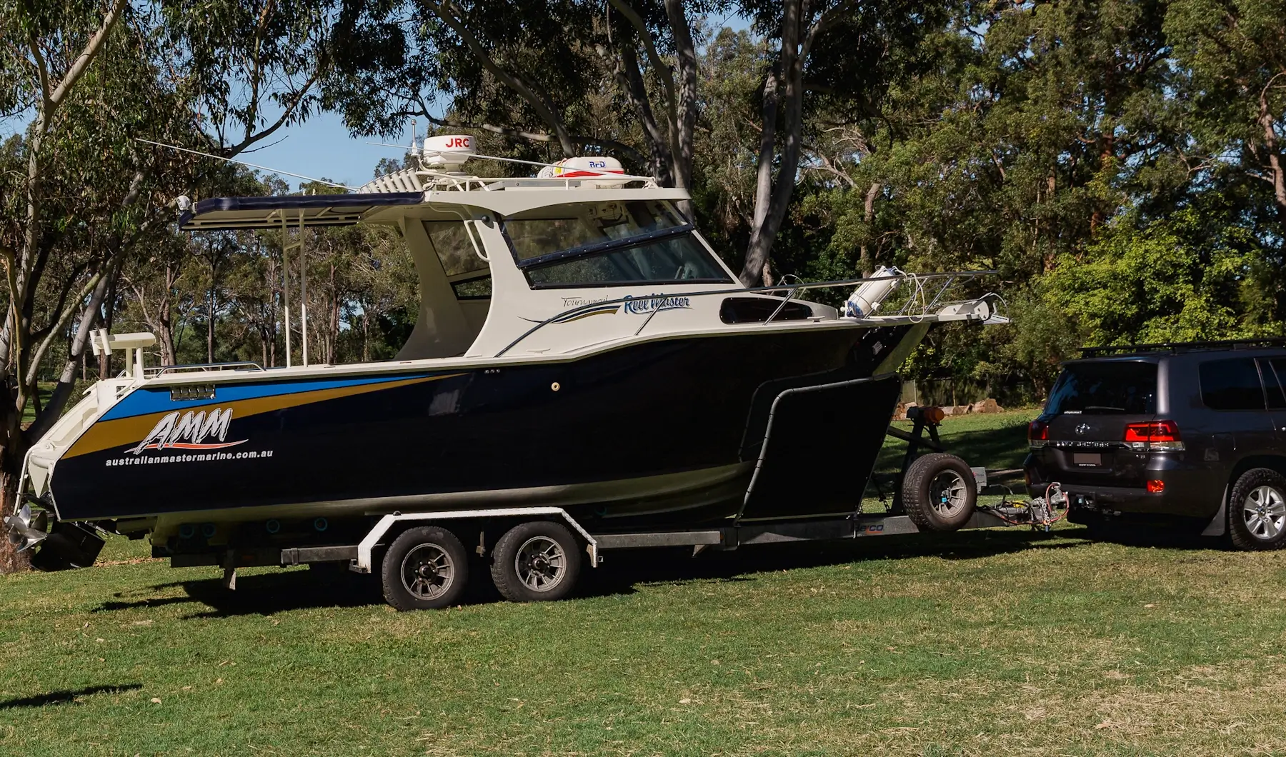 A dark blue boat being towed by a black 4WD through a green park, showcasing Smarter Towing Wheel Sensei’s smart TPMS trailer monitoring for boat owners.